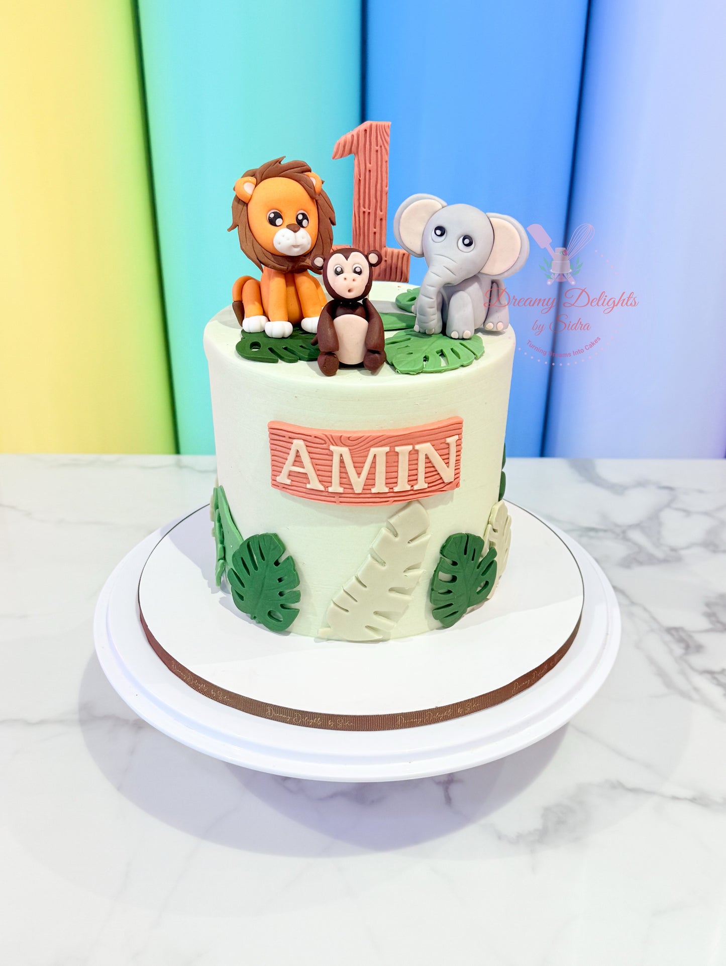 Children's birthday cake with animal figurines and 'Amin' on a colorful background