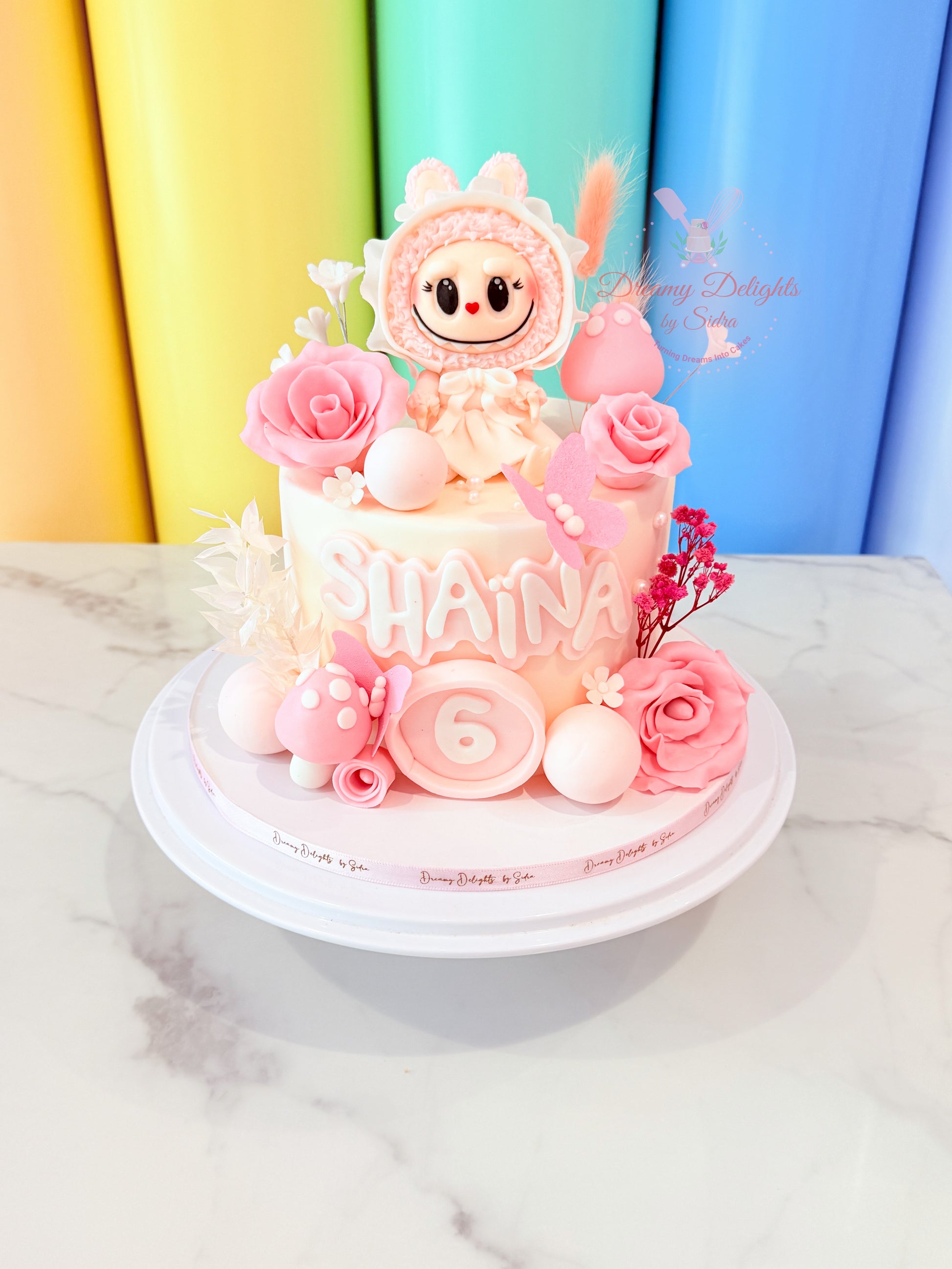 Labubu floral theme birthday cake with pastel flowers and cartoon topper for girls birthday party in Dubai