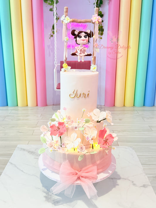 Little girl on swing cake in Dubai girls kids birthday custom themed cake with sugar flowers