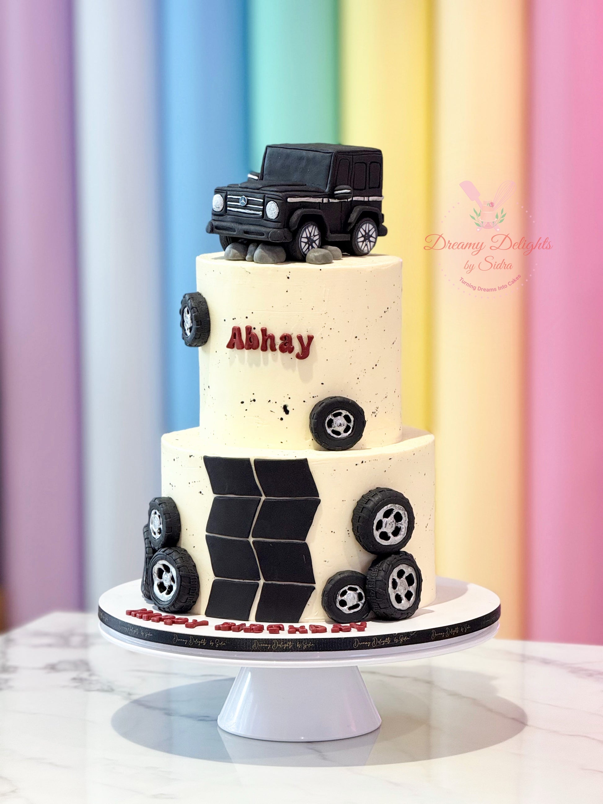 Two-tiered cake with black car design  against a colorful background