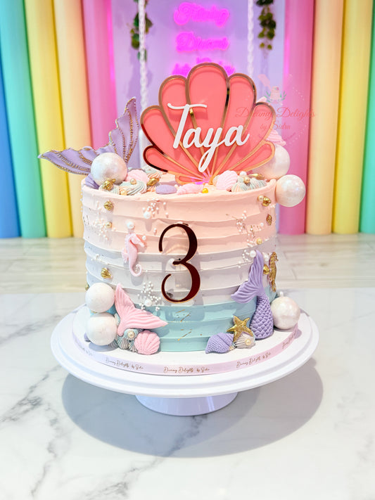 Mermaid tails and shell cake for girls with pastel buttercream finish, fondant mermaid tails, seashell decorations, and ocean theme design