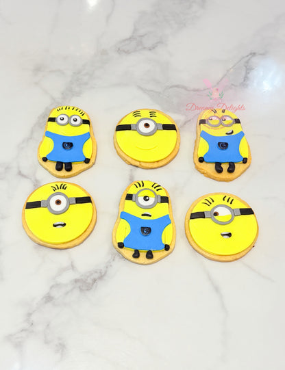 Minion theme cookies decorated with yellow characters, blue outfits and playful expressions by Dreamy Delights by Sidra in Dubai.