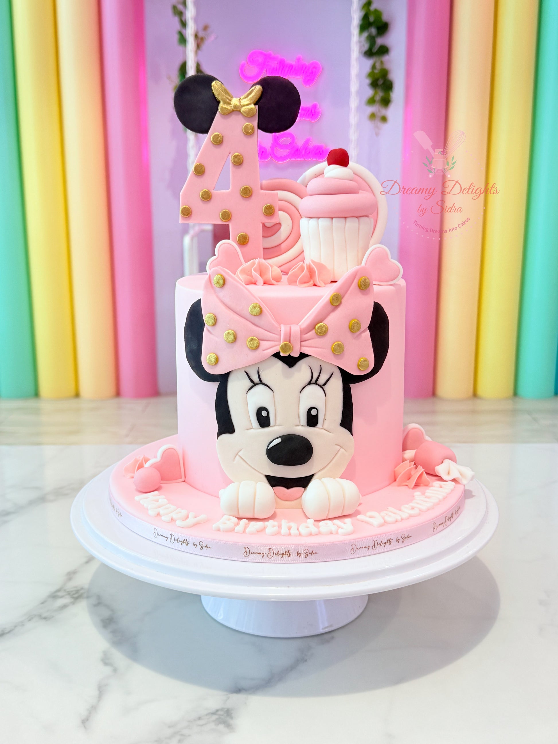 Minnie Mouse themed kids birthday cake for girls with pink cartoon design and bow topper in Dubai
