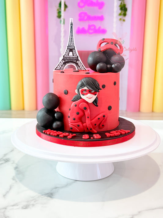 Miraculous cake for girls with red and black superhero theme, fondant character figure, decorative balls, and kids birthday design