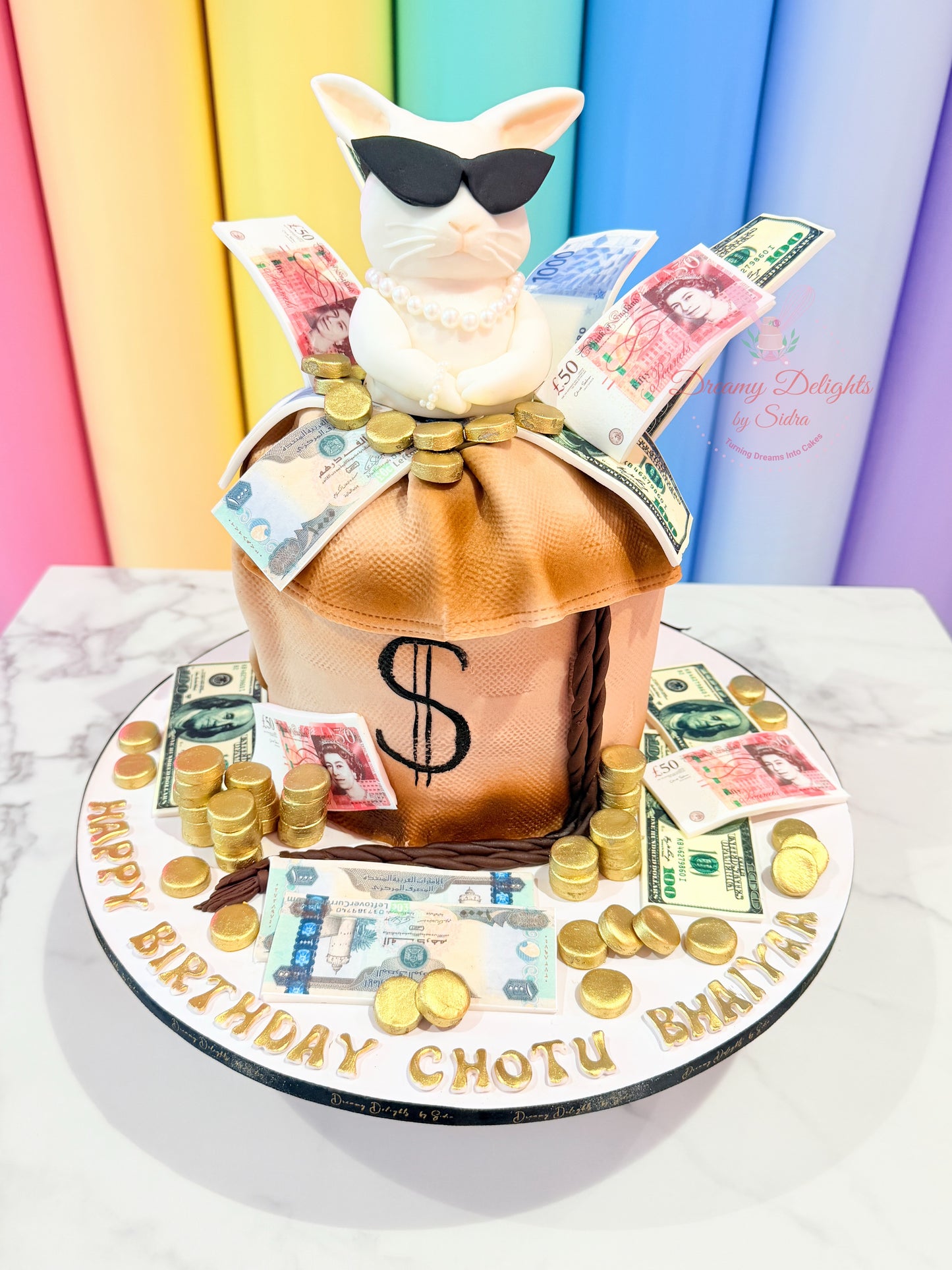Birthday cake with a bottle, money, and a cat figurine against a colorful background