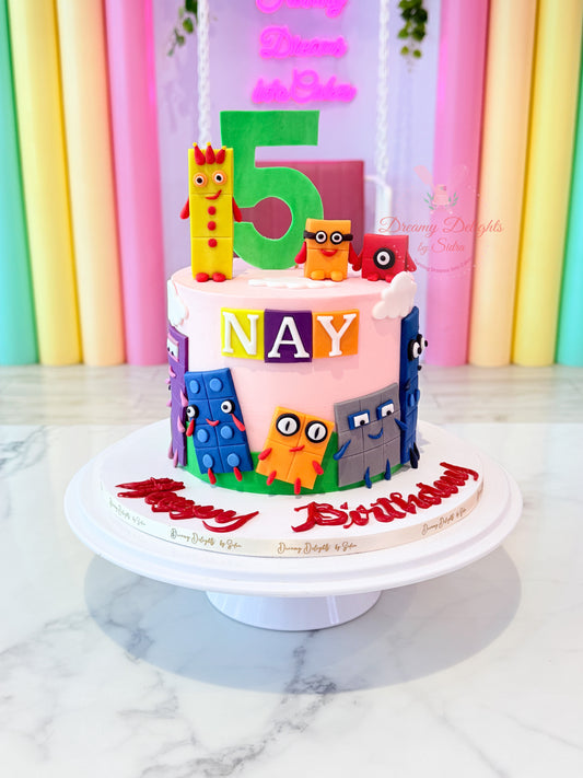 Numberblocks birthday cake with colourful character toppers, custom age number, and personalised name decoration by Dreamy Delights by Sidra in Dubai.