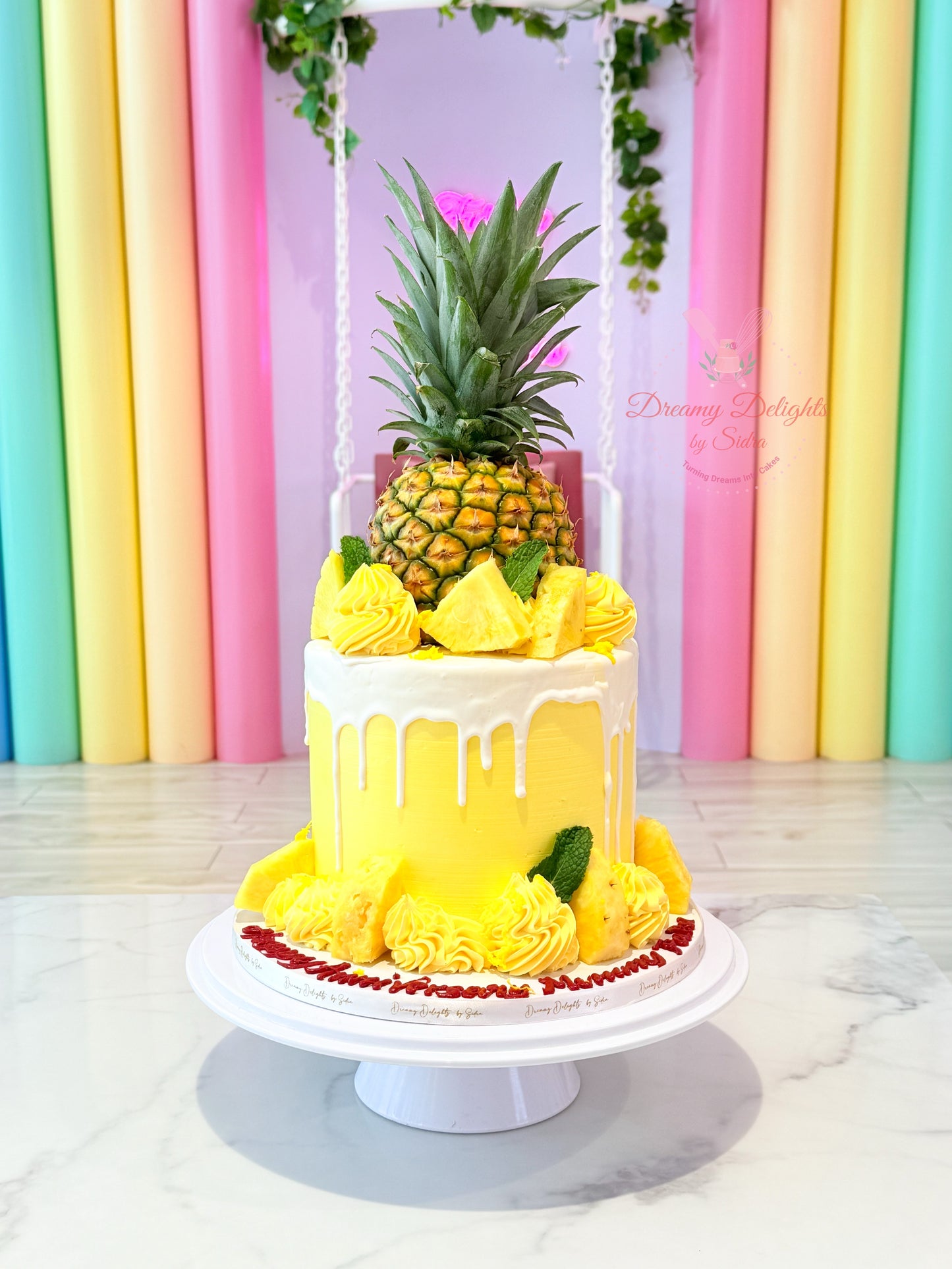 Decorative cake with pineapple and flowers on a stand against a colorful curtain background