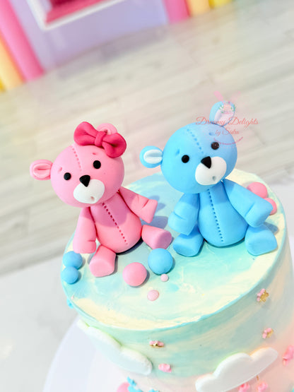 Two teddy bear figurines, one pink and one blue, on a cake with colorful frosting.