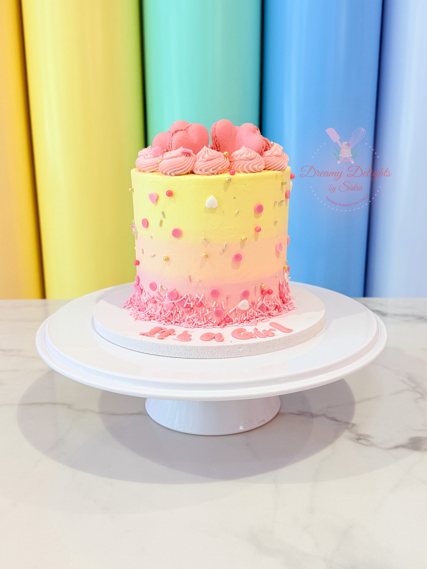 Pastel-colored cake on a white stand with a colorful curtain background