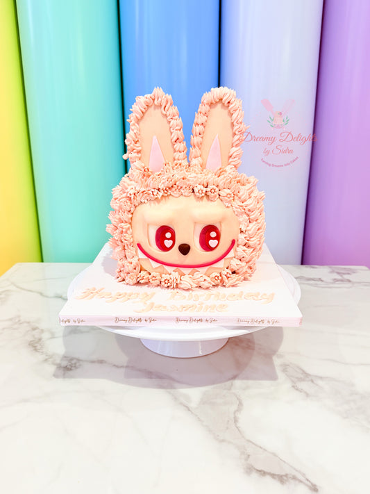 Pink rabbit-shaped cake with decorative ears on a white marble surface against a colorful background.