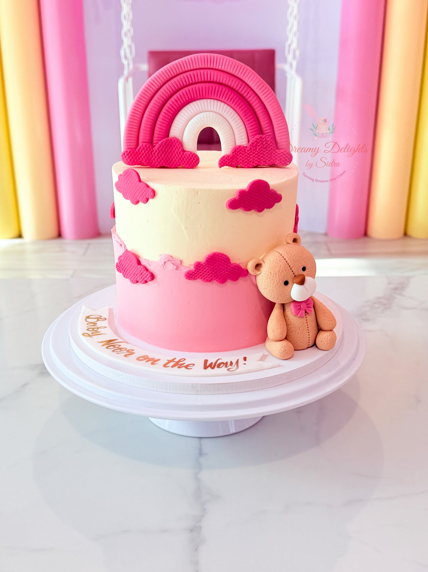 Pink rainbow teddy birthday cake with pastel clouds and teddy topper for girls celebrations in Dubai