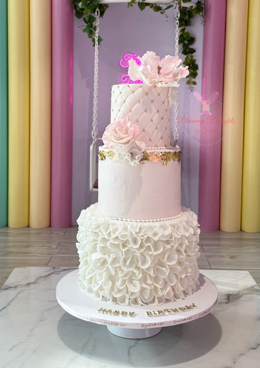 Three-tiered wedding cake with floral decorations on a marble surface against a colorful curtain background.
