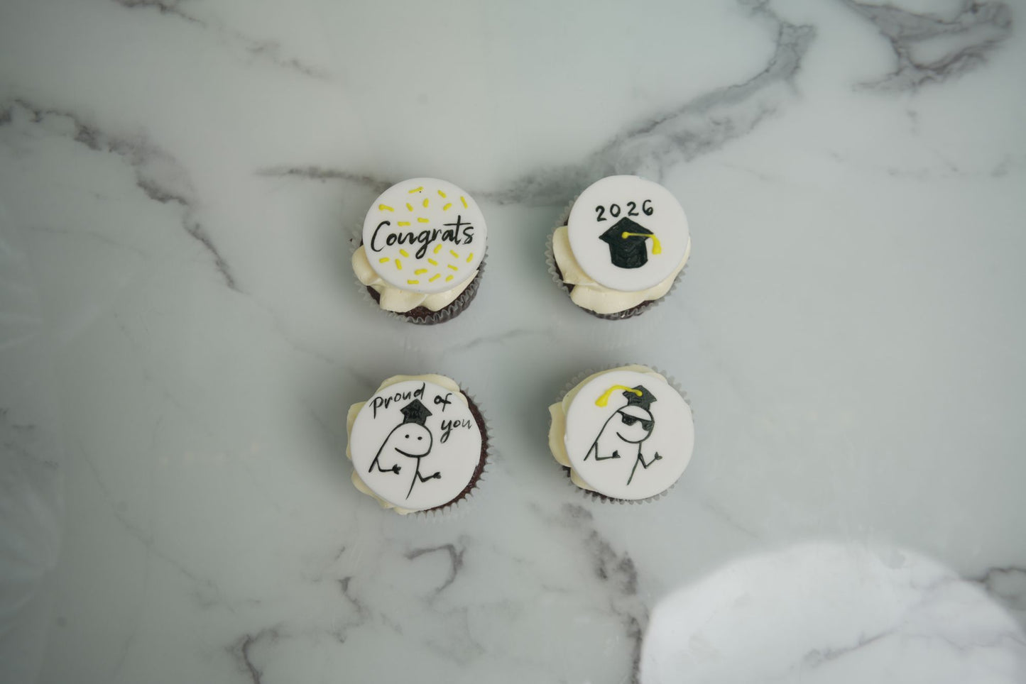 Graduation cupcakes with edible graduation cap toppers, congratulatory messages, and Class of 2026 decorations for graduation celebrations.