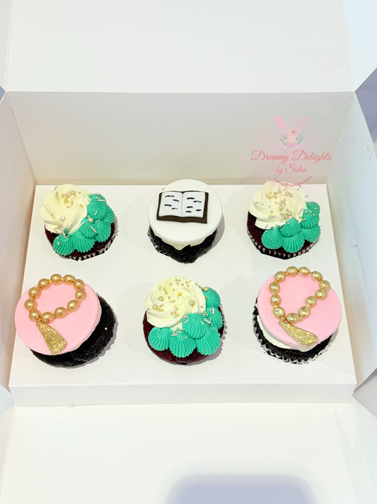 Box of six decorated cupcakes with various designs on a white background
