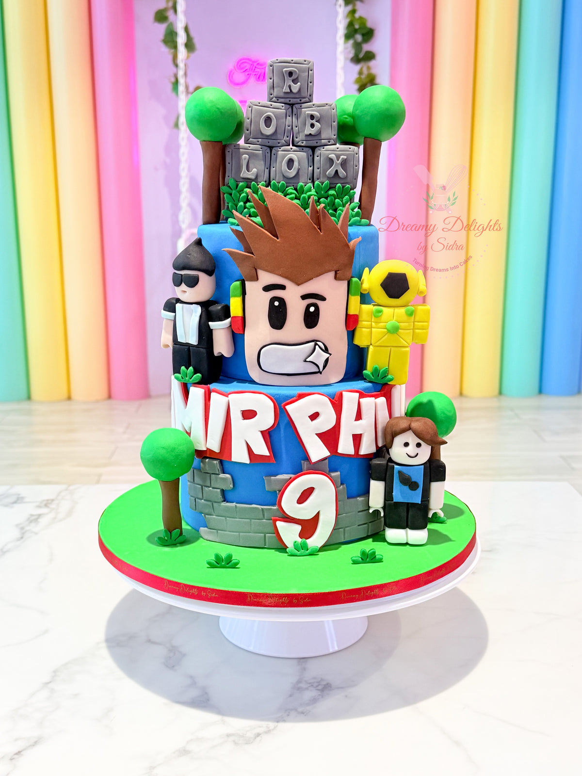 Roblox birthday cake with game characters, block decorations and age topper by Dreamy Delights by Sidra in Dubai.