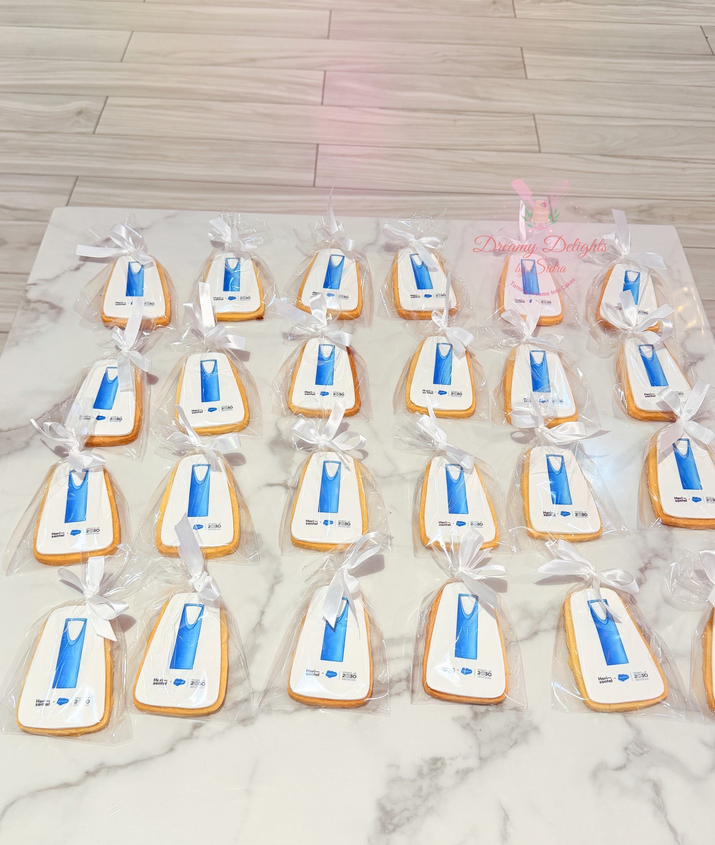 Custom shaped logo cookies individually wrapped with white ribbons for corporate branding, promotional events, and business gifting in Dubai.