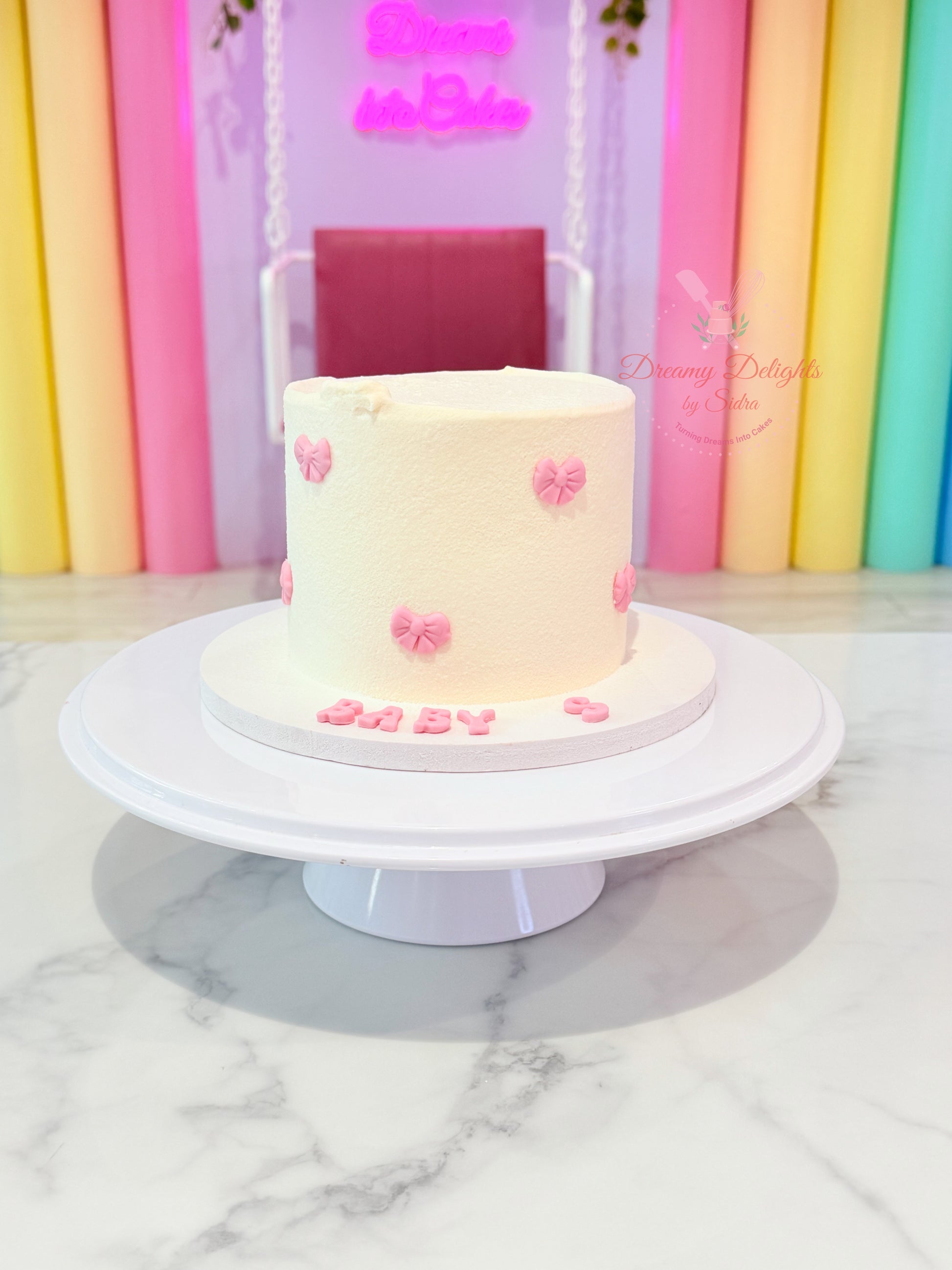 Simple bows birthday cake with handcrafted pink bow decorations and smooth white buttercream finish by Dreamy Delights by Sidra in Dubai.
