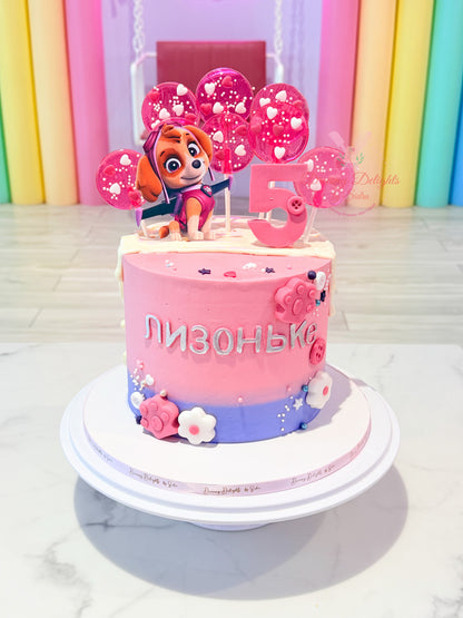 Personalized Skye Paw Patrol birthday cake with pink buttercream, candy lollipop toppers, and custom age decoration for girls in Dubai.
