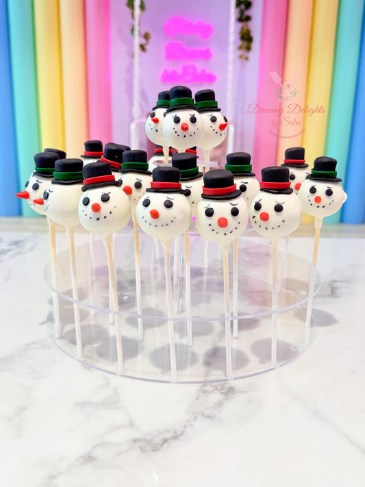 Snowman-themed cake pops on sticks in front of a colorful curtain.
