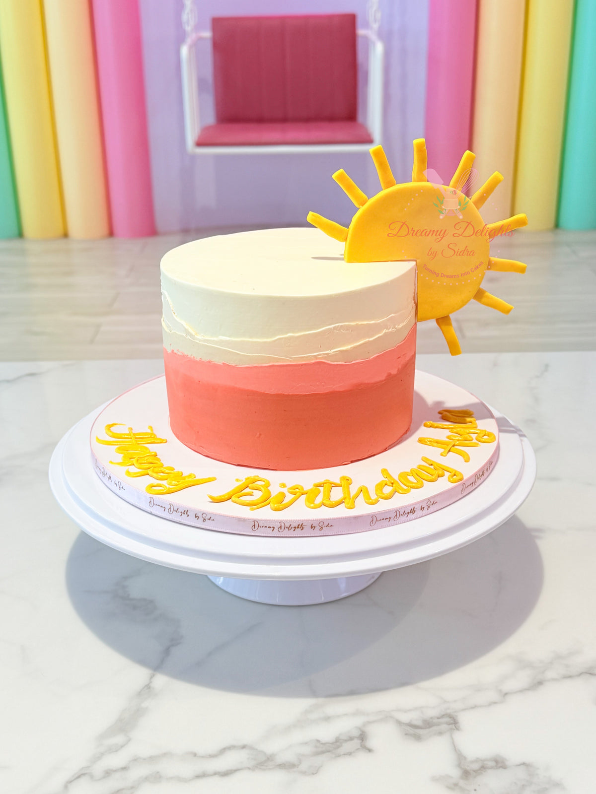 Sunshine girls birthday cake Dubai with coral buttercream and a bright yellow sunshine topper by Dreamy Delights by Sidra