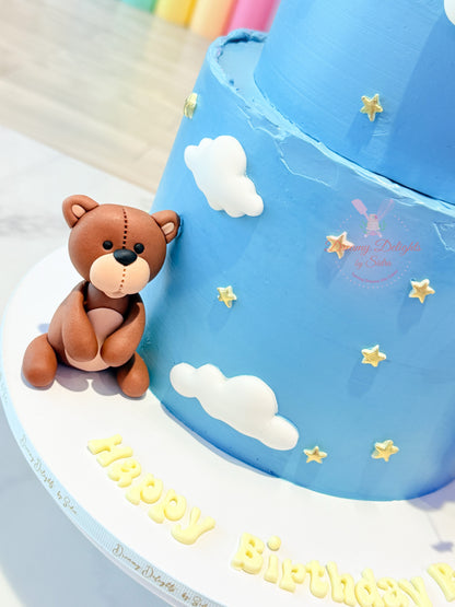 Blue birthday cake with teddy bear decoration and 'Happy Birthday' text
