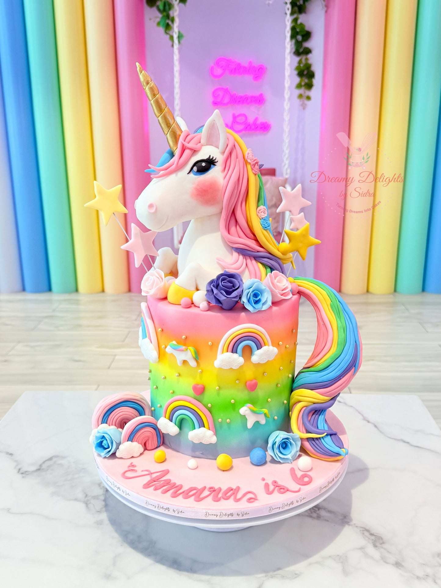 Colorful unicorn cake with rainbow decorations on a marble surface against a colorful curtain background.