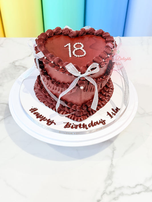 Vintage burgundy heart cake with piped frosting, ribbon bows and pearl details by Dreamy Delights by Sidra in Dubai.