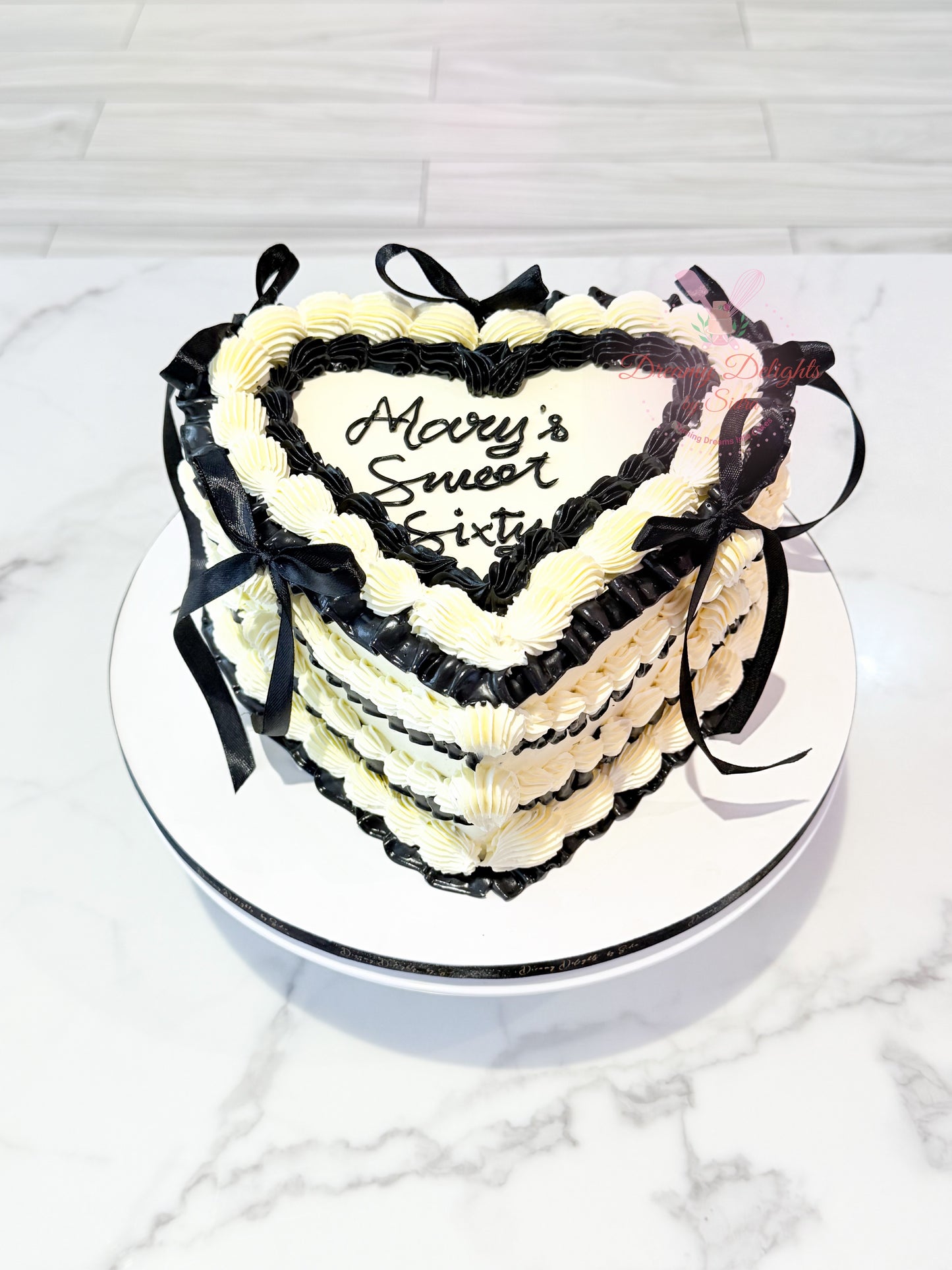 Elegant vintage heart cake with black and white buttercream piping and ribbon decoration for birthdays and celebrations in Dubai.