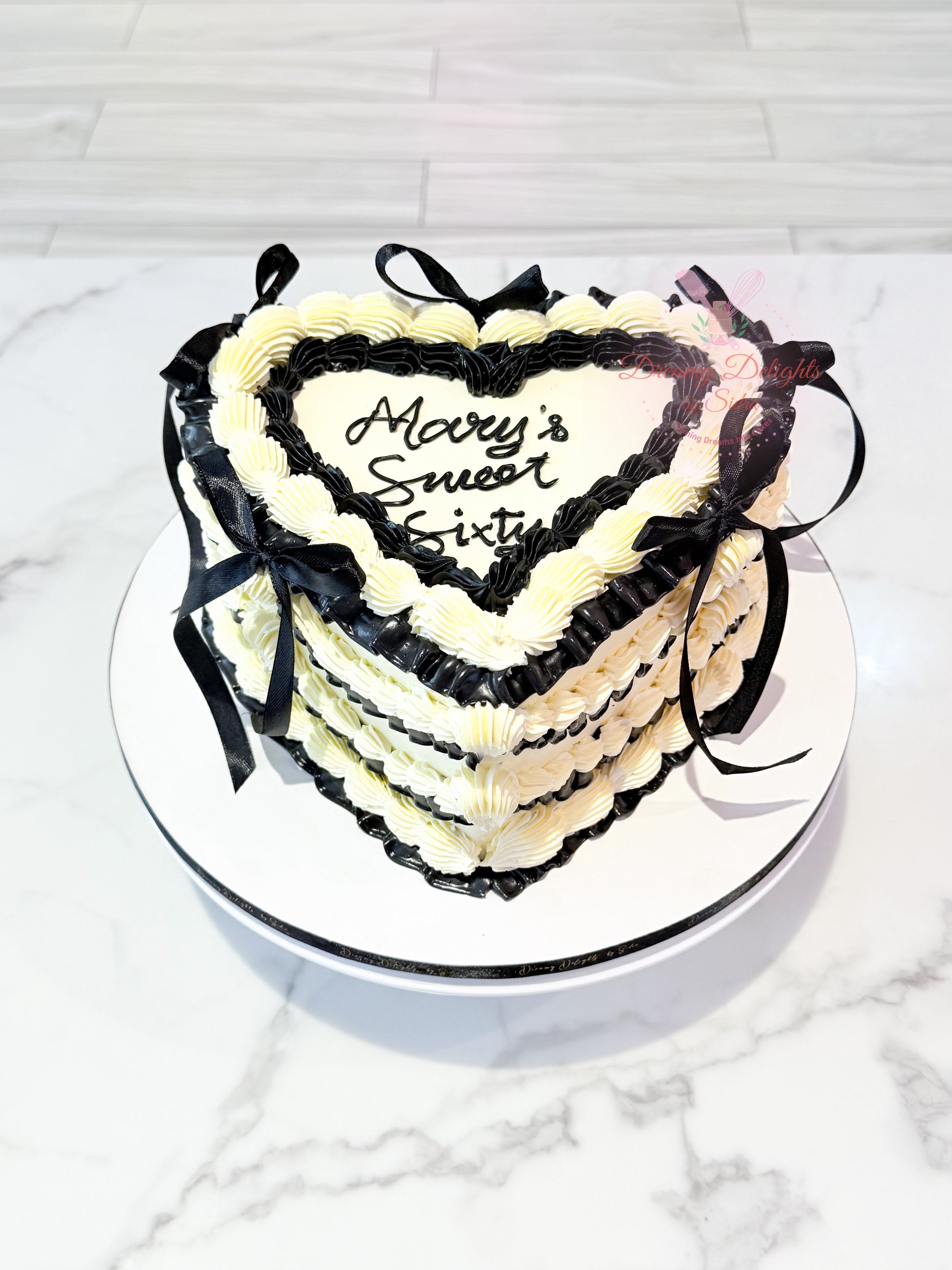 Elegant vintage heart cake with black and white buttercream piping and ribbon decoration for birthdays and celebrations in Dubai.