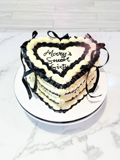 Elegant vintage heart cake with black and white buttercream piping and ribbon decoration for birthdays and celebrations in Dubai.