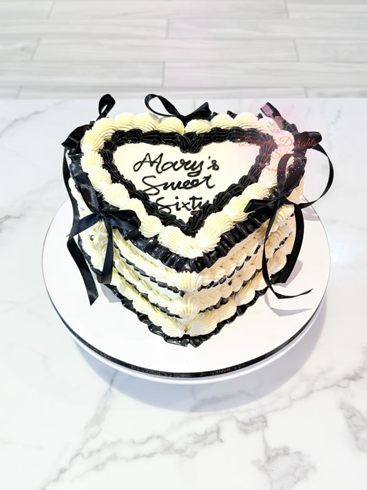 Elegant vintage heart cake with black and white buttercream piping and ribbon decoration for birthdays and celebrations in Dubai.