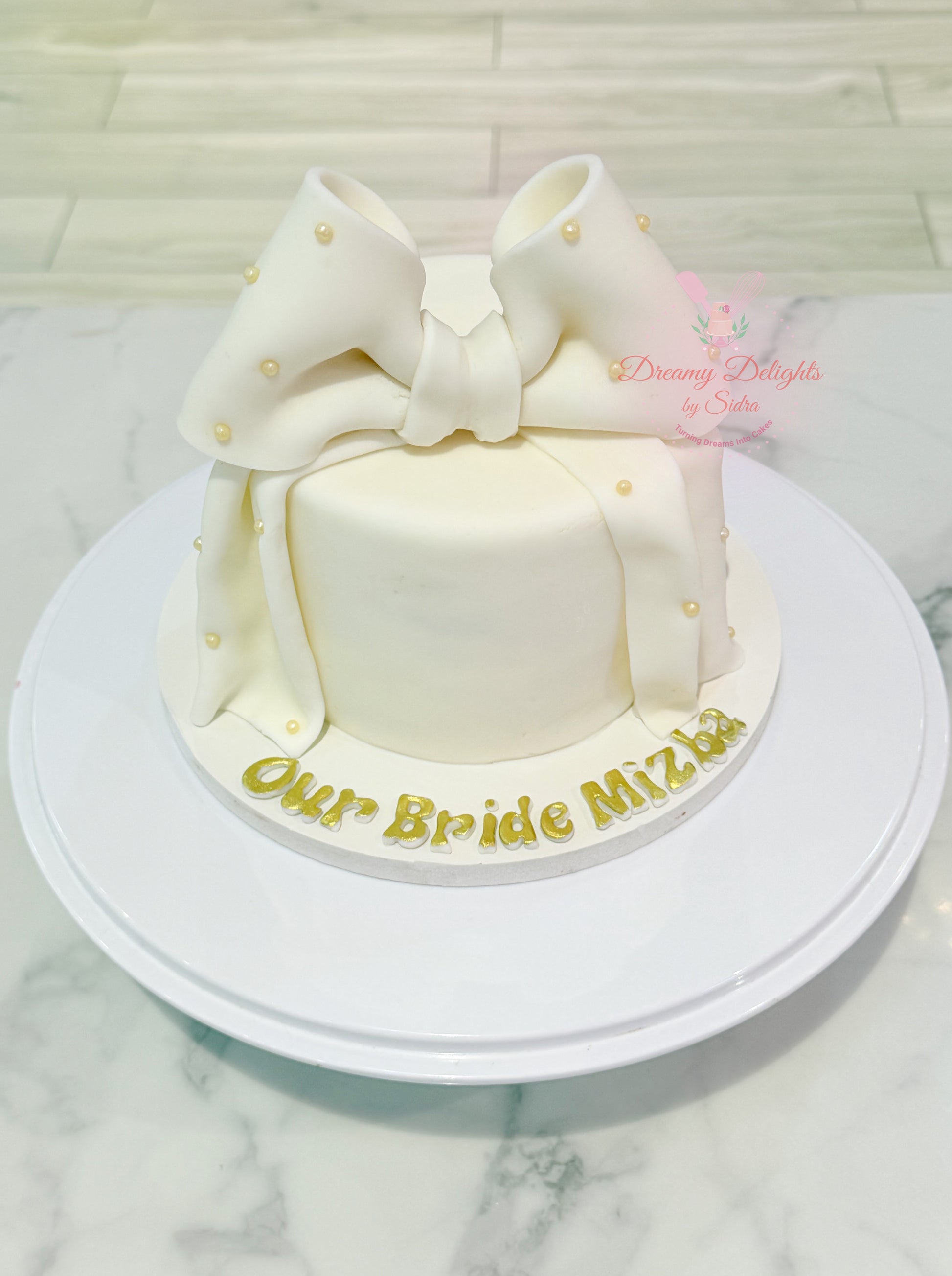 White Big Bow birthday cake featuring an oversized fondant bow, edible pearl details, and elegant white finish by Dreamy Delights by Sidra in Dubai.